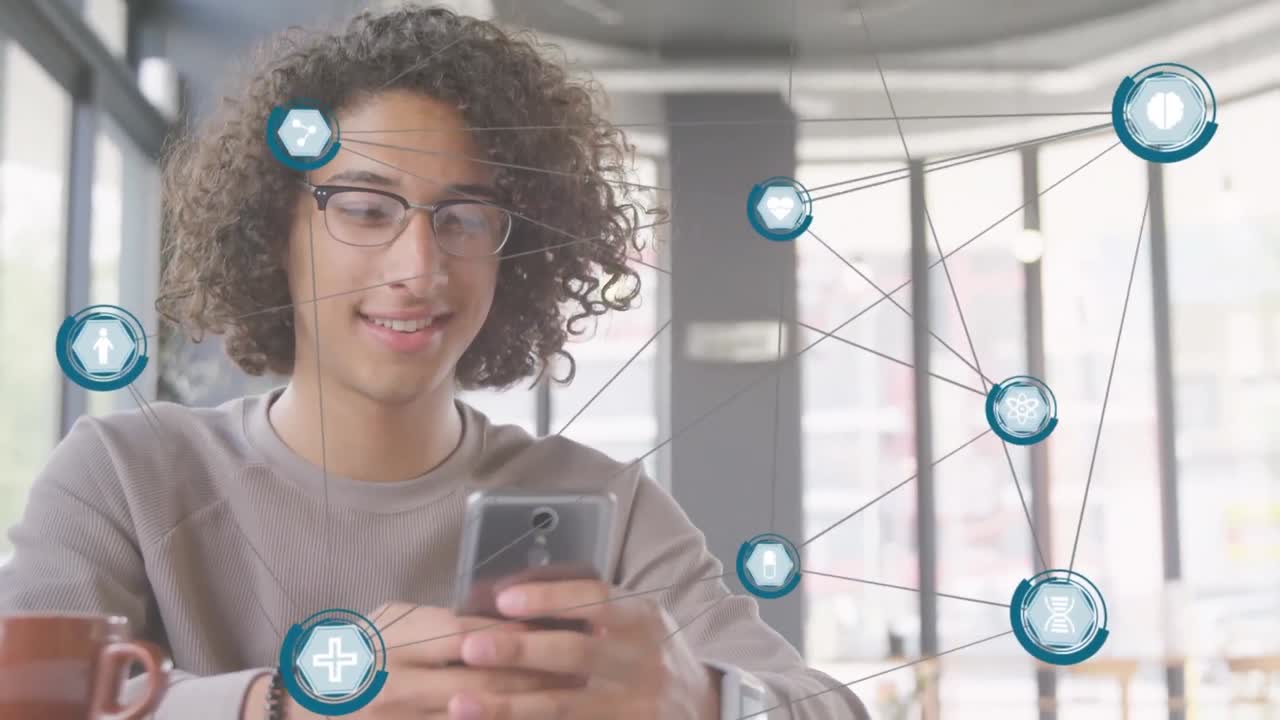 animación de una red de iconos digitales contra un hombre biracial sonriendo mientras usa un teléfono inteligente en una cafetería