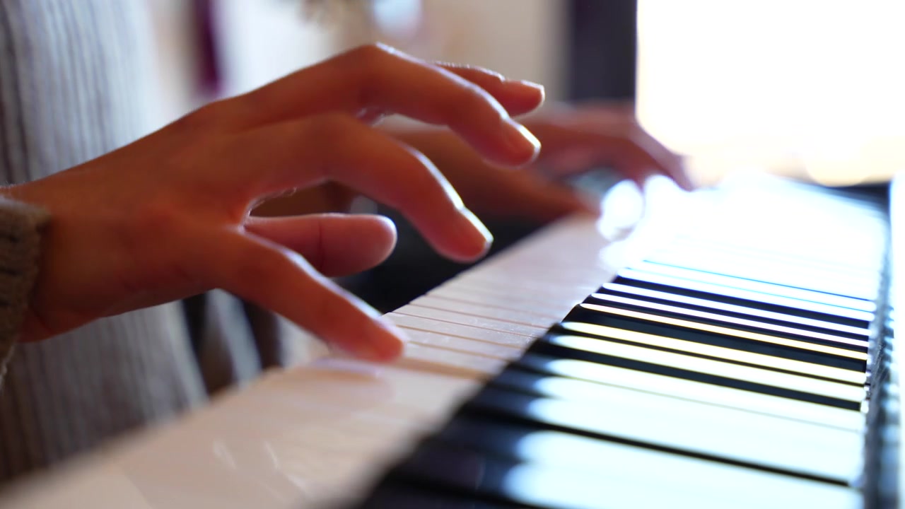 Close up of a musician's hands playing a song on an electric piano keyboard in a living room