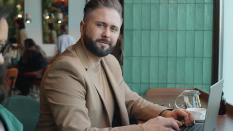 retrato de un apuesto hombre de negocios con una computadora portátil en un café
