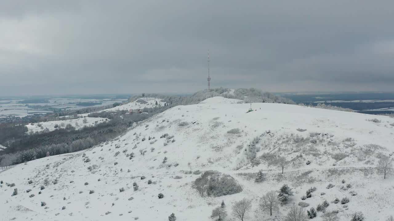 Aerial view of a snowy mountain with a communication tower