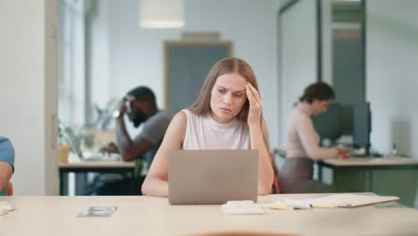 young woman receiving bad letter on laptop in office. sad freelance woman