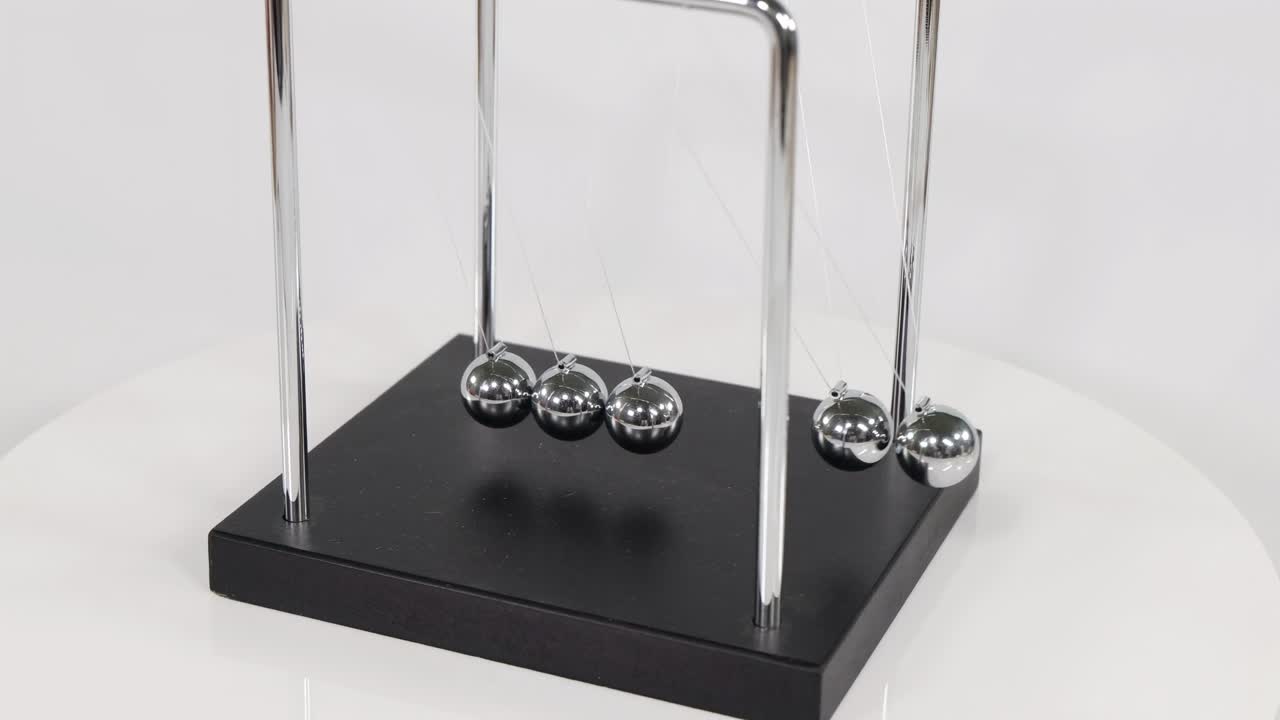 A detailed look at the motion of spheres in a Newton's Cradle on a black base.