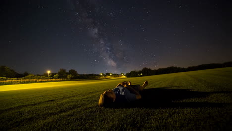 person lying on grass stargazing at the milky way at night