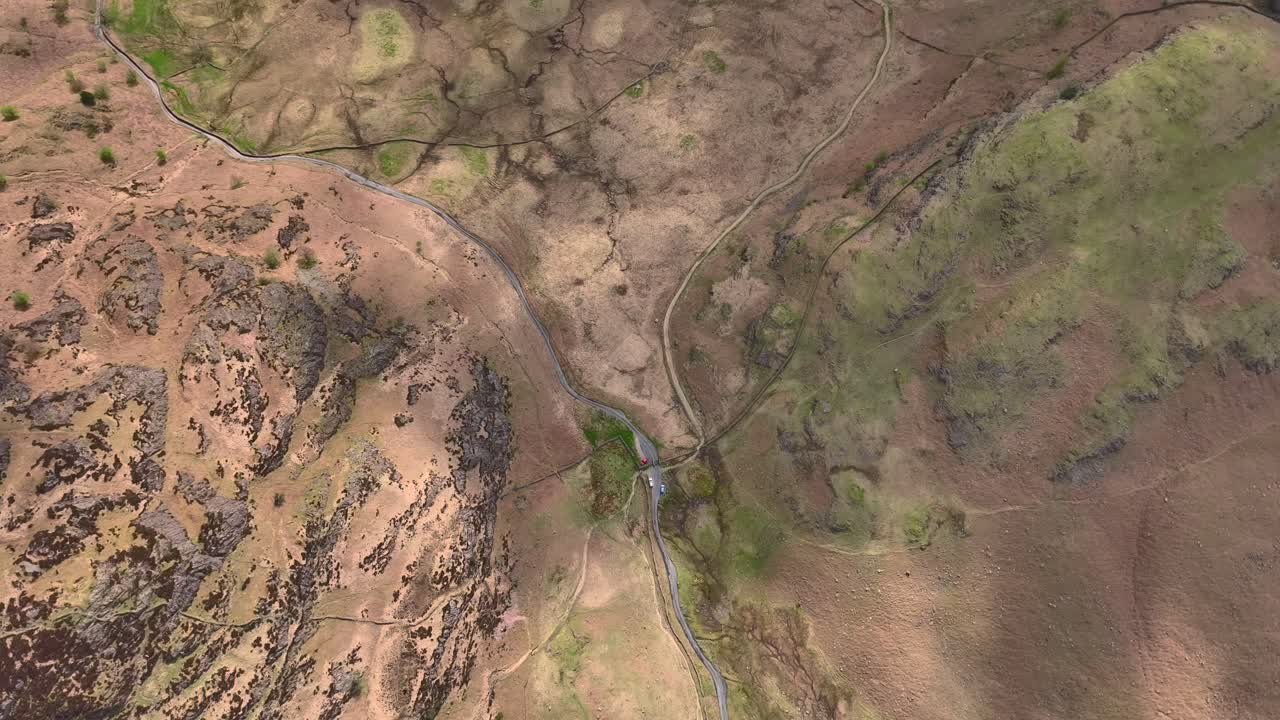 paso de montaña vista de arriba hacia abajo desde la altitud que muestra la carretera del paso de montaña y los coches estacionados