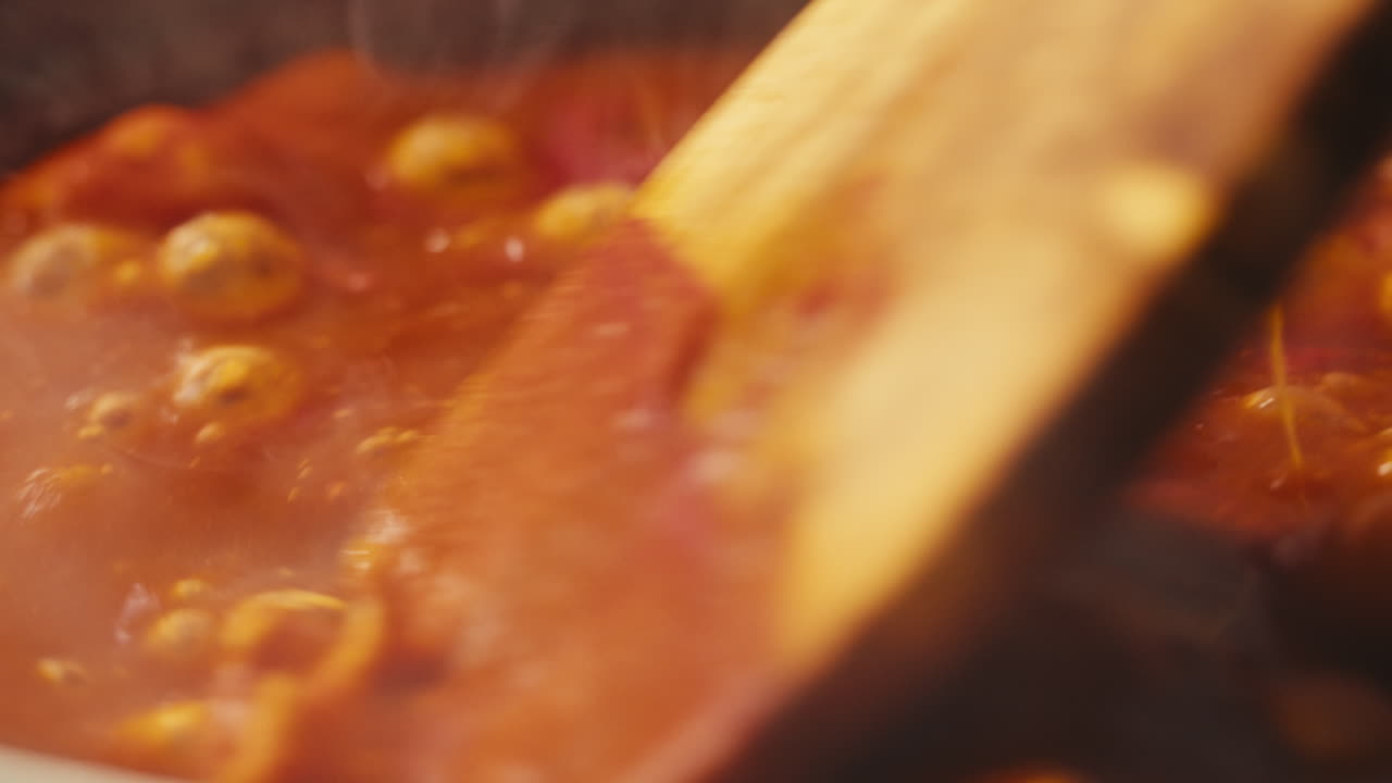 Chicken in tomato sauce is boiling on a frying pan with spices. Cooking tomato sauce curry with chicken fillet. Traditional Italian Mexican Asian dish. High quality studio shot for cafe, restaurant close up.