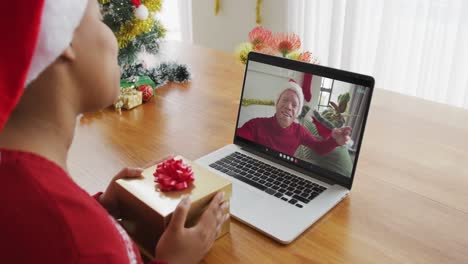 Afroamerikanische-Frau-Mit-Weihnachtsmütze-Nutzt-Laptop-Für-Weihnachtsvideoanruf-Mit-Mann-Auf-Dem-Bildschirm