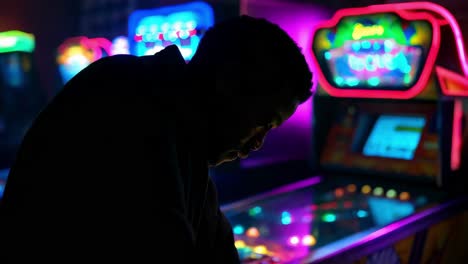 man playing arcade games at night