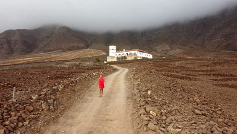 a woman in a red dress is walking down a small road from casa winter