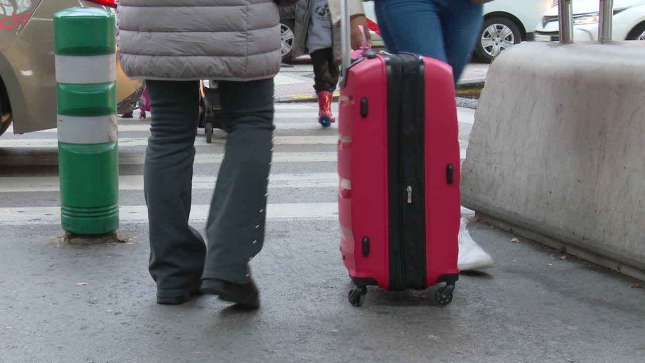 People with luggage crossing a street