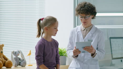 female doctor and little girl using tablet during checkup