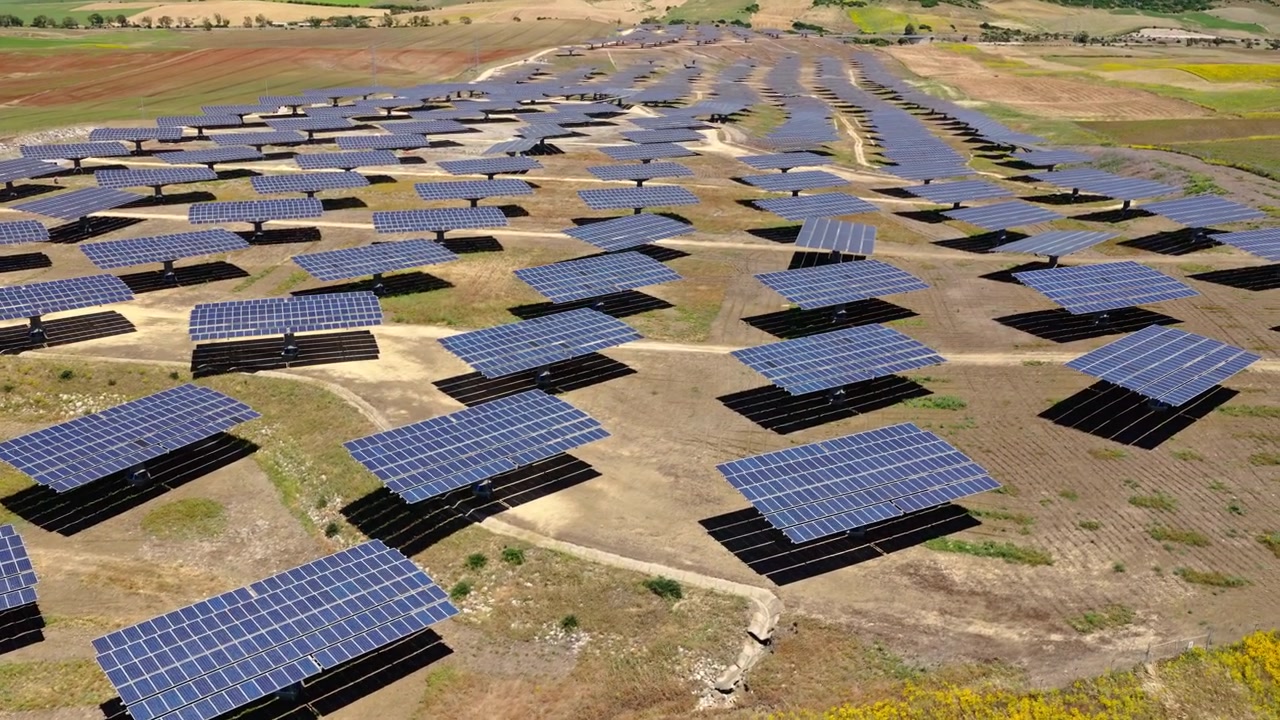 Filmisk droneoptagelse flyver over et stort solcelleanlæg med fotovoltaiske paneler, der genererer ren, vedvarende elektricitet. Bæredygtig energiinfrastruktur, der understøtter den globale energiovergang.