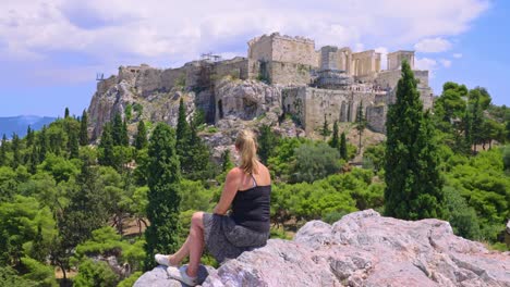 rear view of female looking at view of acropolis and parthenon from areopagus hill in athens, greece