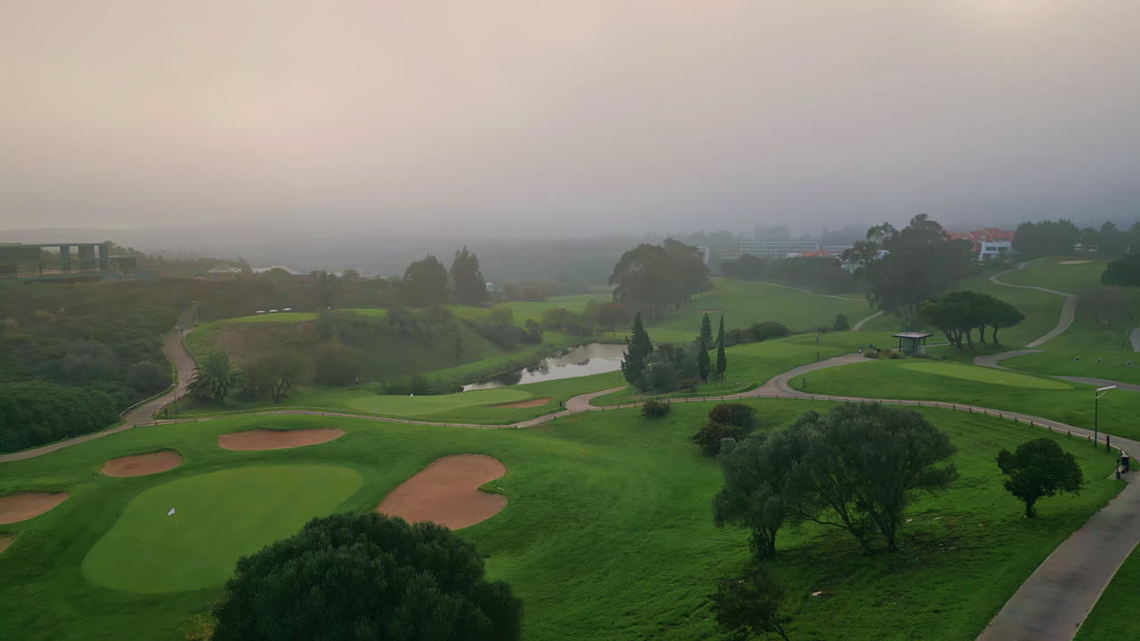 Drone misty morning descending on golf course. Fog covering field greenery