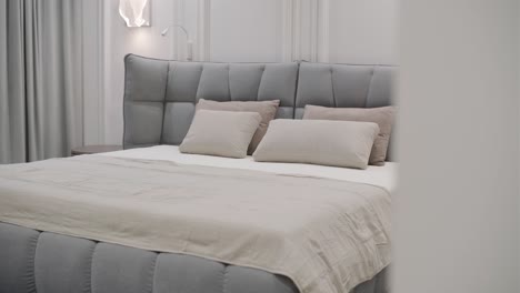 a modern bedroom showcases a large upholstered bed with a tufted headboard in gray tones, complete with coordinated bedding and pillows