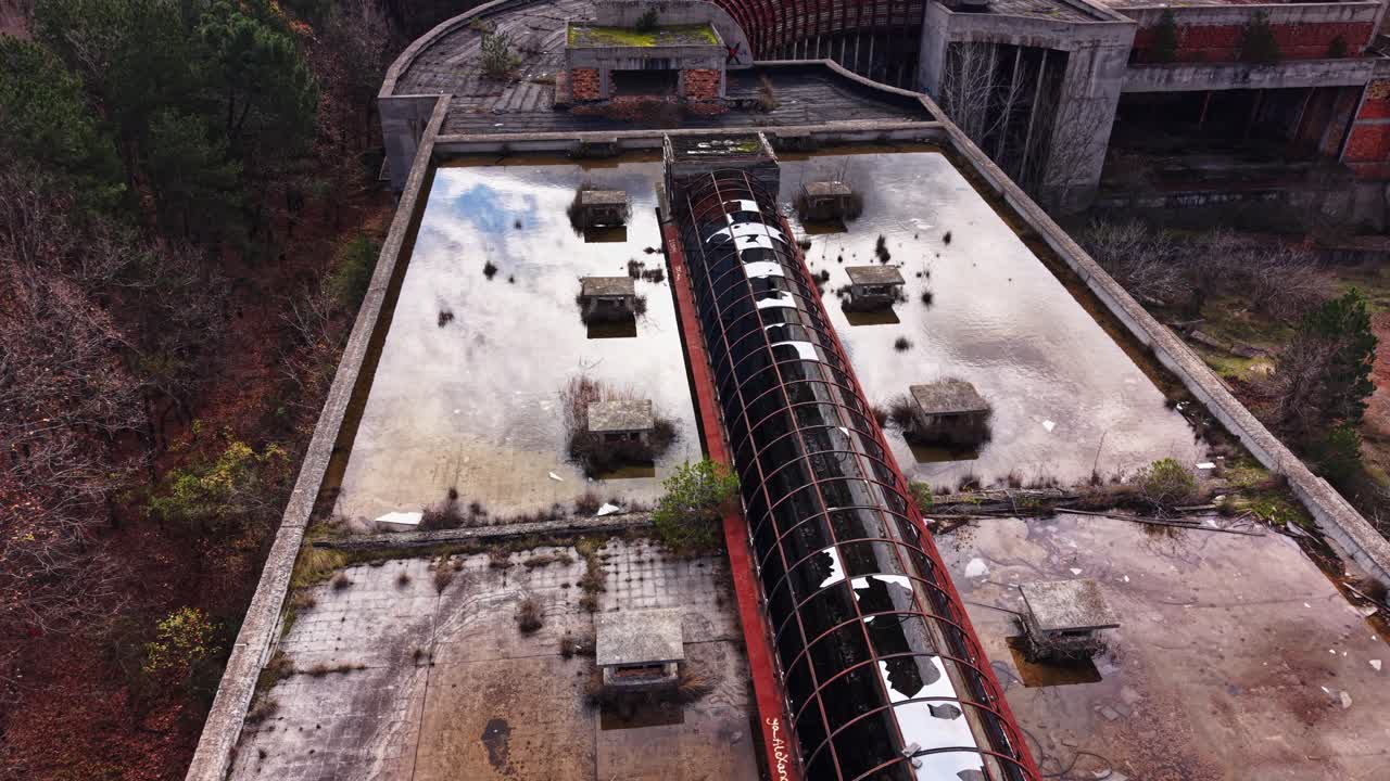 Abandoned industrial site with overgrown structures and still water
