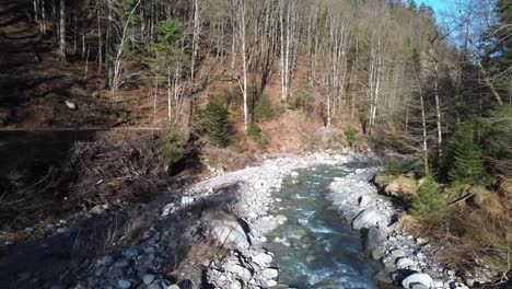 Flying-above-Clear-Blue-River-with-small-Road-next-to-it