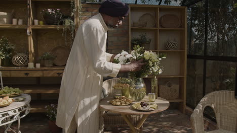 elderly man arranging flowers and snacks in a greenhouse