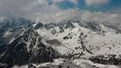 air flight through mountain clouds over beautiful snow-capped peaks of mountains and glaciers.