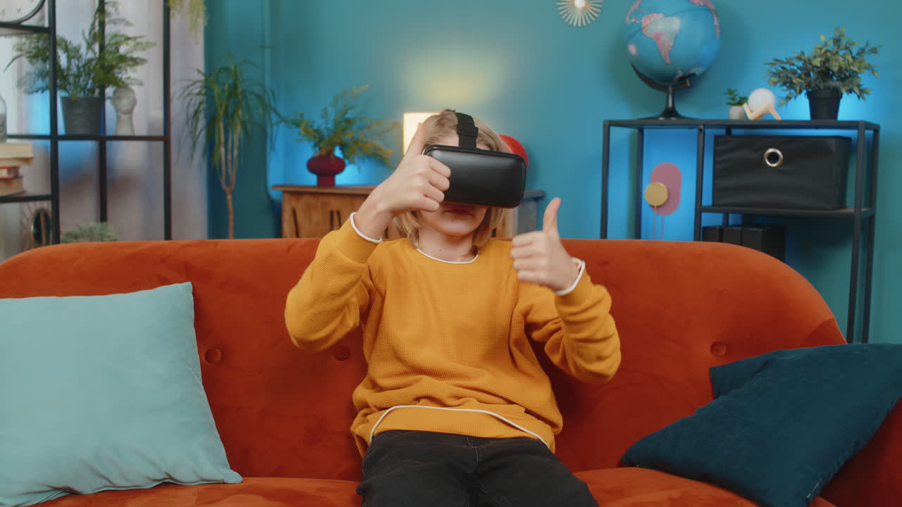 Ragazzo adolescente che gioca con entusiasmo alla realtà virtuale, agitando le mani e mostrando stupore, seduto sul divano di casa