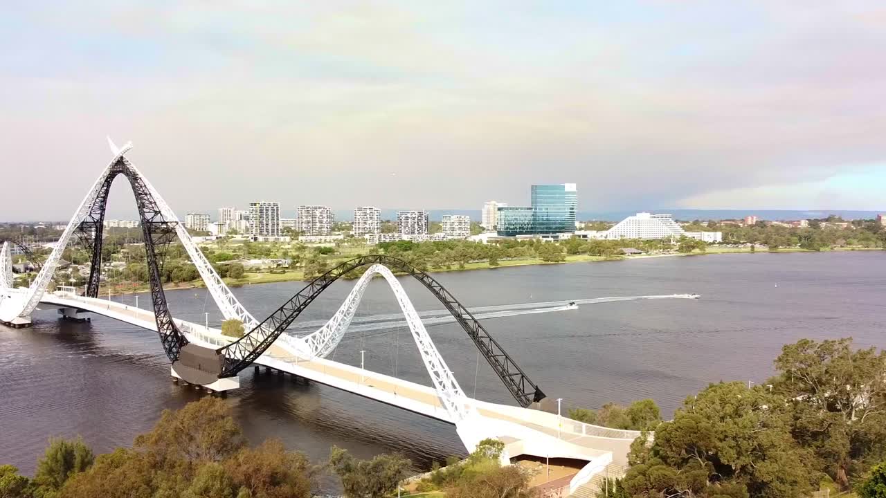 Aerial tracking shot of two speedboats racing under the Matagarup Bridge and along the Swan River, Perth