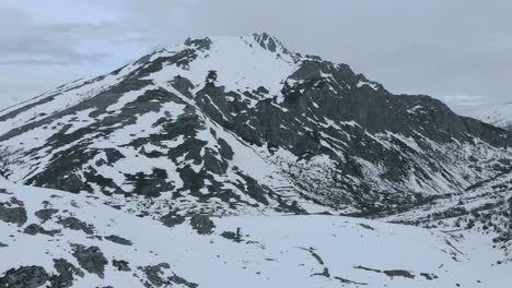 Drone-Aéreo-Eis-Aleja-Montañas-Rocosas-Nevadas-Y-Un-Lago-Congelado-En-Isoba,-Ruta-De-Senderismo-Encantadora-Y-Mística-Con-La-Niebla-De-Las-Nubes-Cerca