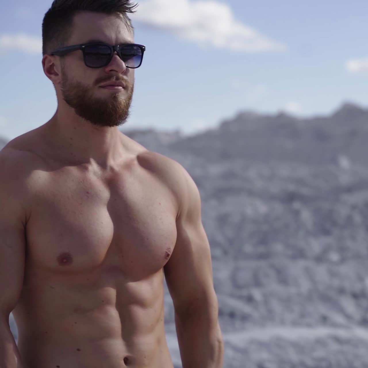 Bearded sportsman in sunglasses. Shirtless guy with muscular body on white canyon background. Healthy bodybuilder outdoors.
