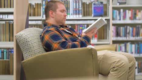 el hombre se sienta en la biblioteca leyendo un libro