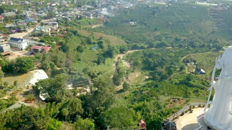 Drone footage of giant religious statue and Elephant waterfall on stones in Vietnam, Dalat. Village and road with pond and trees and nature.