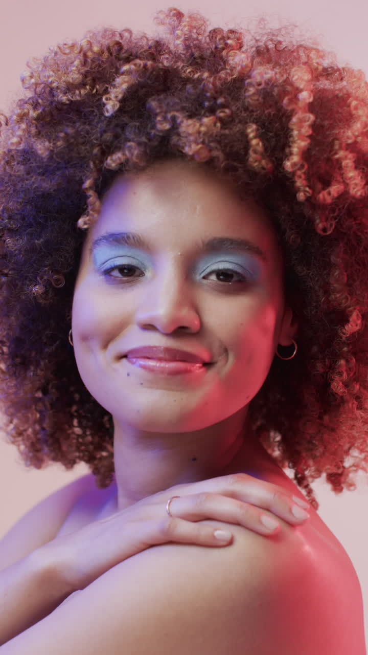Vertical video of biracial woman with dark hair in blue and pink light, slow motion