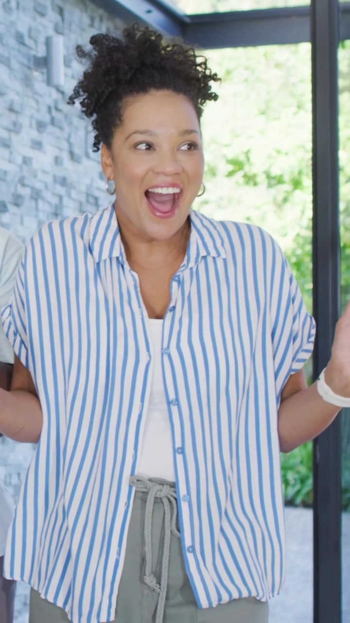 Vertical video: Clapping woman in striped shirt and watch reaching hugging partner at home reunion