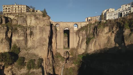 vista aérea del puente nuevo en ronda, españa, moviéndose hacia atrás durante la puesta de sol con un cielo azul claro