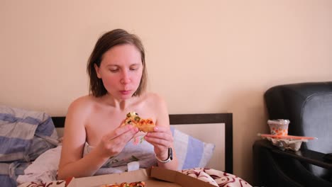 view of a circle of pizza lying in a crust on the lap of a girl who eats it with pleasure, at home.