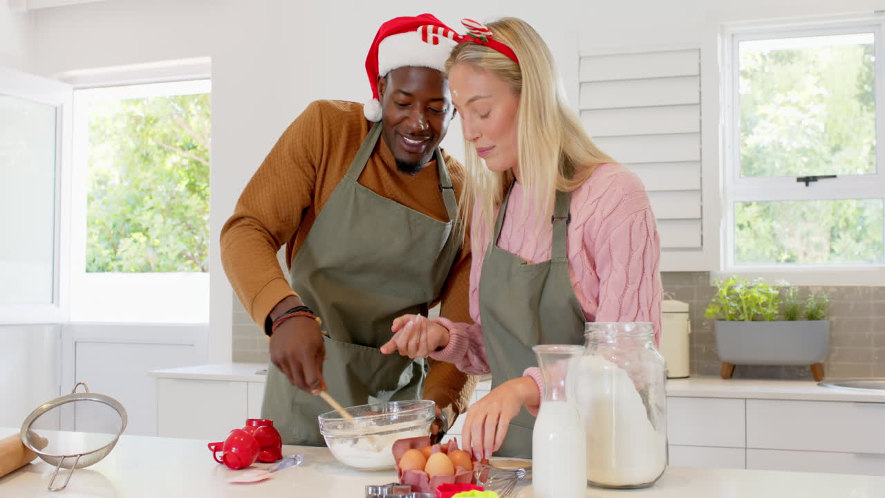 Weihnachtszeit, vielfältiges Paar backt gemeinsam in der Küche, trägt festliche Kleidung.