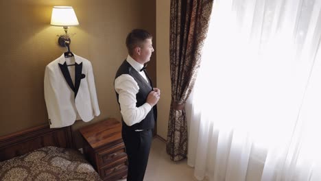 groom buttoning jacket, man in suit fastens buttons on his jacket preparing to go out