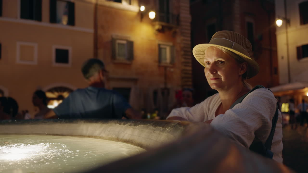 Woman by a fountain at night in Rome