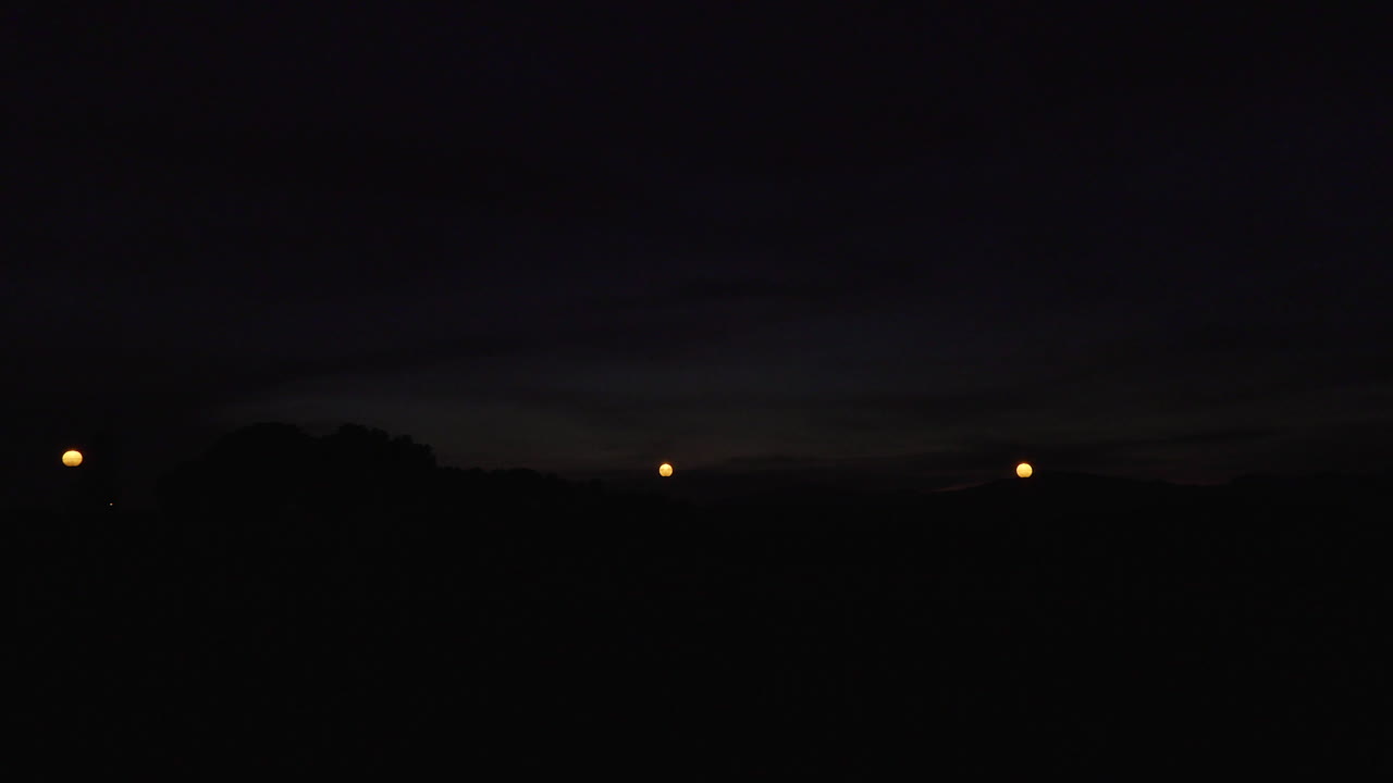 Timelapse of the last lights of the day in a small town. The sun illuminates the clouds below leaving beatiful and pink colors