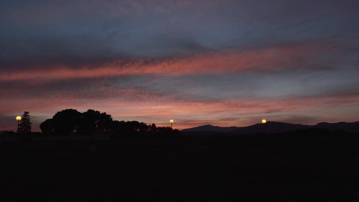 Timelapse delle ultime luci del giorno in una piccola città. Il sole illumina le nuvole sottostanti lasciando colori bellissimi e rosa.