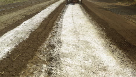 reveal shot of a tractor working in a crop land mixing and amending the soil ground, agribusiness concept