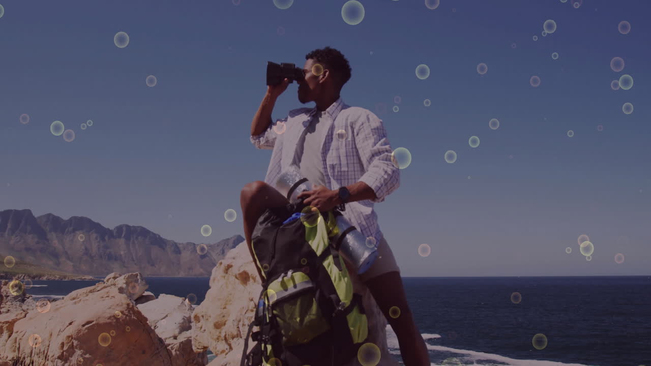 man scanning coastal cliff with binoculars, showing animated graph and compass icons for technology