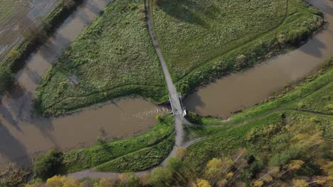 Aerial-tilt:-Muddy-water-flows-under-small-bridge-in-rural-agriculture