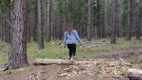 young girl walking between tall trees in a forrest