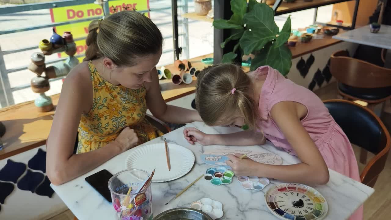 madre e hija disfrutando de una clase de pintura de cerámica