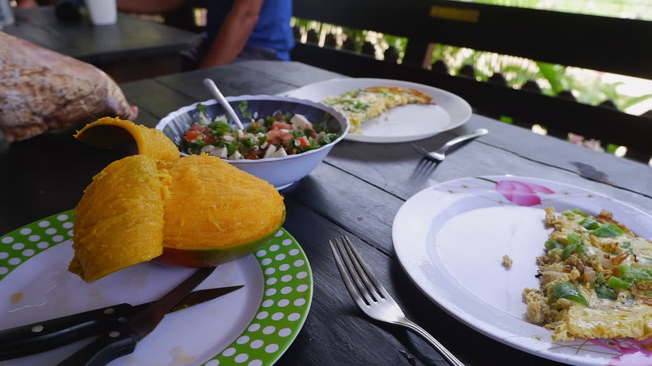tortilla de huevo, mango fresco y ensalada griega en una mesa rústica al aire libre