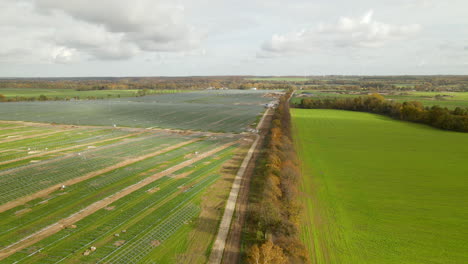 Vuelo-Aéreo-Hacia-Atrás-De-Una-Gran-Granja-Solar-Durante-La-Fase-De-Construcción---Campo-Agrícola-Con-Innovación-Tecnológica