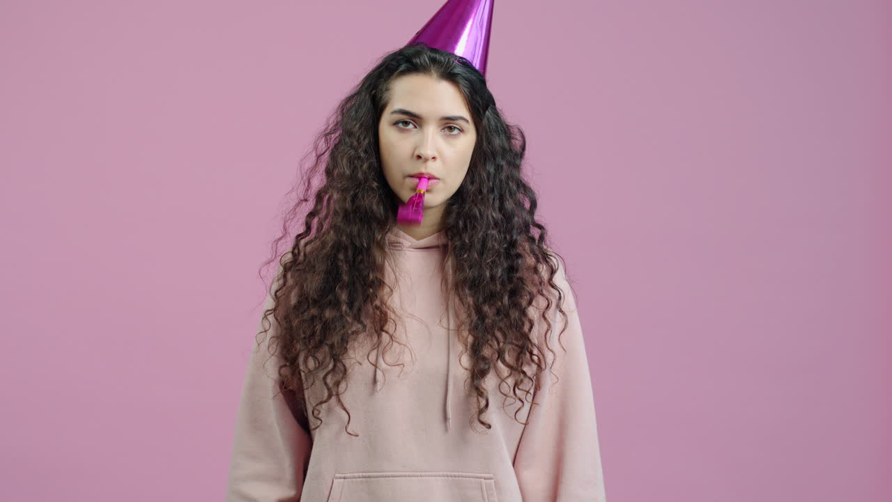 Woman celebrating a birthday with a party hat and horn