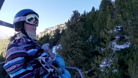 Junge-Frau-Auf-Einem-Sessellift-über-Den-Pisten,-Die-Die-Natürliche-Winterlandschaft-Mit-Schnee-Und-Kiefern-Genießen