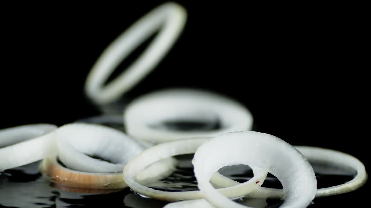 los anillos de cebolla caen sobre el agua con salpicaduras.