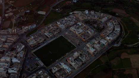 cityscape and football field in dingli, malta during sunset - aerial drone shot