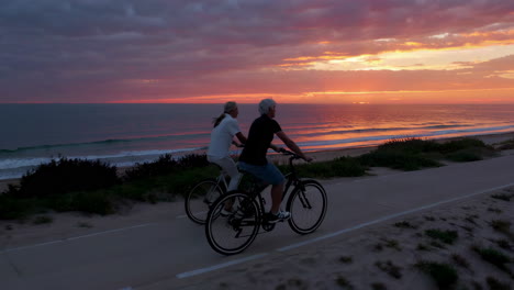 couple cycling along beach path at sunset