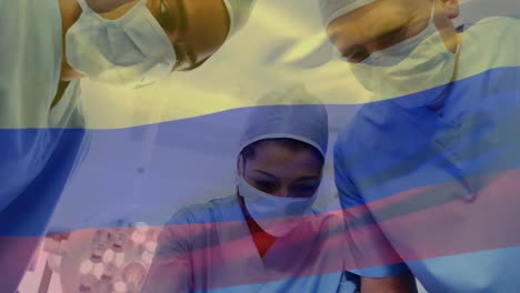 animation of waving colombia flag over team of diverse surgeons performing surgery at hospital